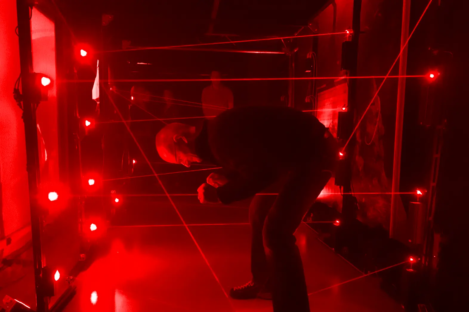 Teilnehmer im Laser Labyrinth zwischen sichtbaren Laserstrahlen